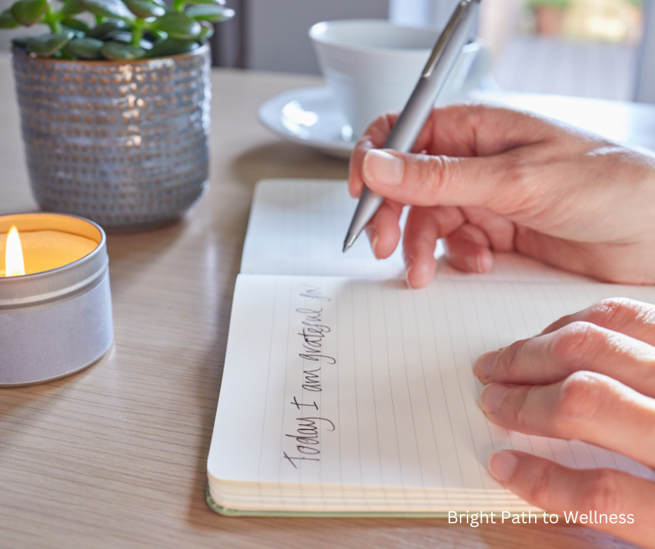 A person writing in a notebook 'Today I'm grateful for...' and a candle next to it.