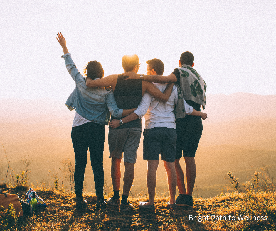 A group of friends hugging in front of the valley and the sunset.