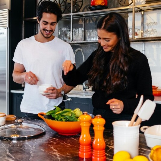 Two friends preparing a salad in the kitchen