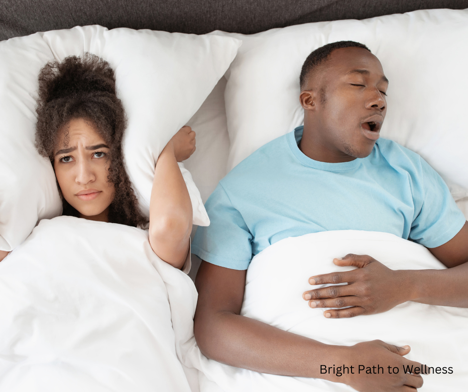 Impact of snoring on a relationship. A couple lying in bed, the man snoring and the woman awake covering her ears with the pillow.
