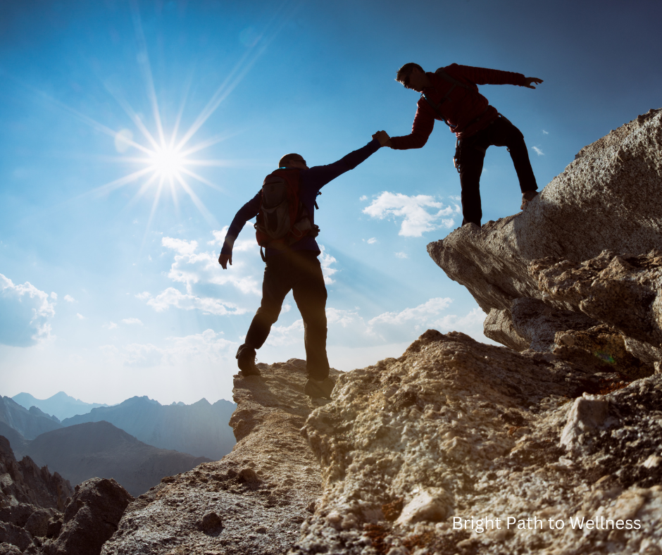 Two people climbing a mountain, and one helping the other up.