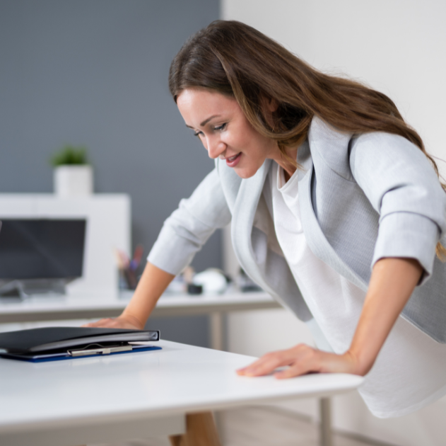 A woman doing quick exercises as part of movement snacking, integrating short bursts of physical activity into her daily work routine.