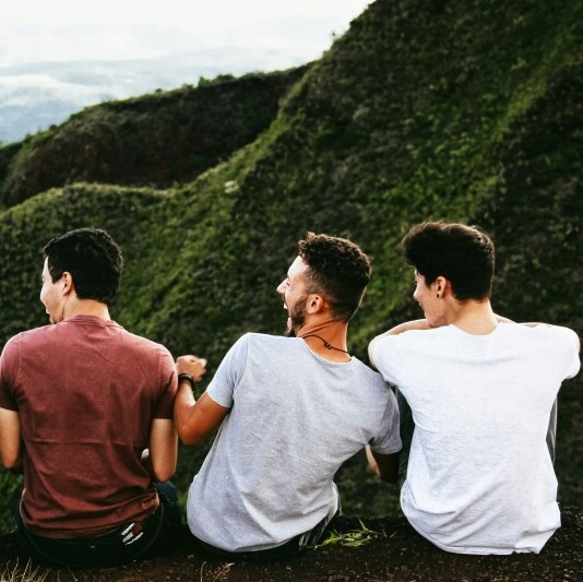 Friends sitting in front of a valley, laughing.