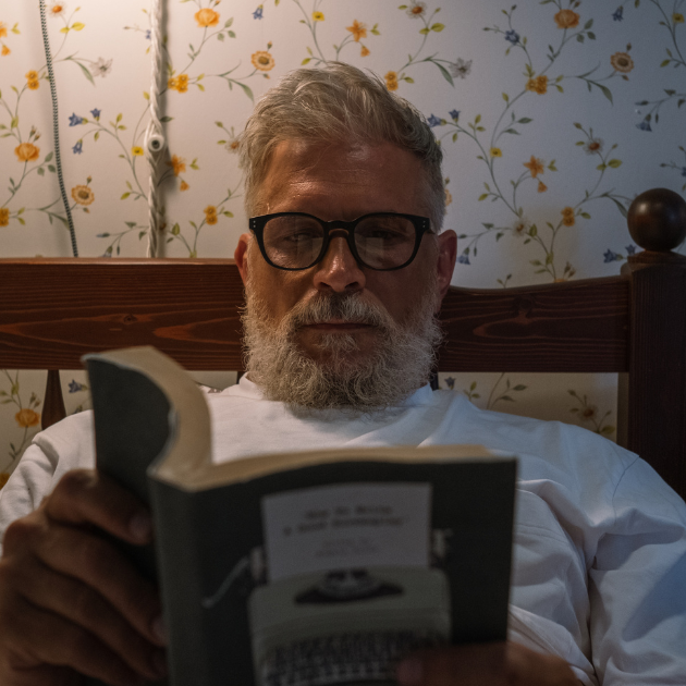 Person unwinding with a book before sleep in a cozy, screen-free environment.